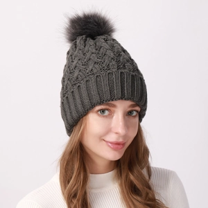 Dettaglio del cappello in maglia grigio scuro con pompon e bordo a coste elastico