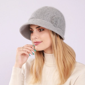 Detail of grey knitted winter bucket hat with plush floral decoration on the side