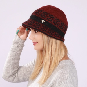 Detail of dark red knit visor hat for women with a golden bee brooch and floral pattern