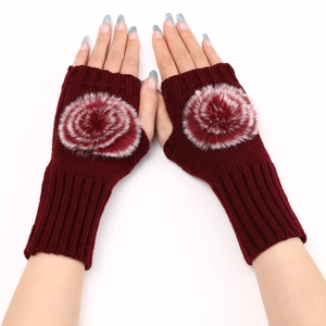 Détail de mitaines en tricot bordeaux avec pompons décoratifs en fausse fourrure