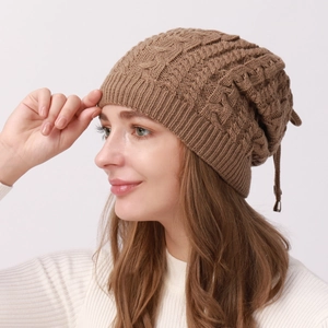 Detail of dark brown cable knit beanie with ribbed hem and decorative drawstring cord
