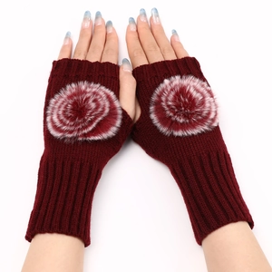 Détail de mitaines en tricot bordeaux avec pompons en fausse fourrure et poignets côtelés