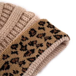 Detail of cable knit texture and leopard print cuff on a thick beige winter hat