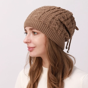 Detail of brown cable-knit slouchy beanie with adjustable drawstring and metal buckle