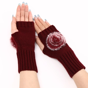 Gros plan de mitaines en tricot bordeaux avec détail de pompon rouge et blanc doux