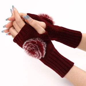 Détail des mitaines en tricot bordeaux avec pompon duveteux portées sur les mains