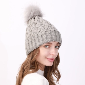 Trama dettagliata del cappello invernale in maglia grigia con pompon in ecopelliccia