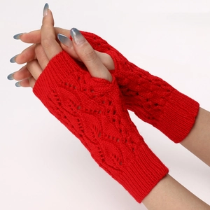 Detail of red cable knit fingerless gloves with hollow leaf pattern and soft wool texture