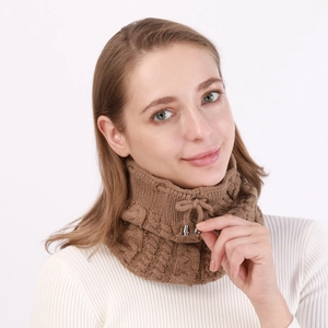 Detail of cable-knit texture and metallic drawstring toggles on a brown neck warmer