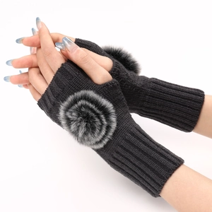 Détail de mitaines en tricot gris foncé avec pompons en fausse fourrure sur le dessus