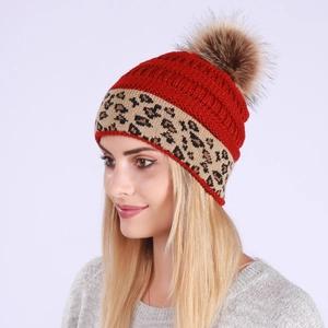 Women's red knit beanie with leopard print cuff and large fluffy faux fur pom-pom