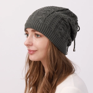 Close-up of dark grey cable knit beanie showing thick texture and adjustable drawstring