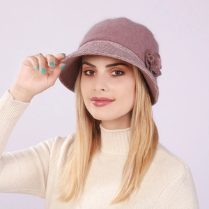 Detail of a dusty pink knitted hat featuring wool texture and decorative floral accent