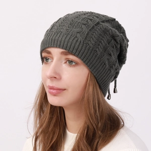 Detail view of dark grey cable knit beanie with elastic ribbed brim on a female model