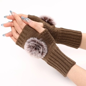 Détail du tricot des mitaines marron foncé ornées de pompons en fourrure synthétique