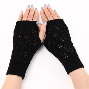 Close-up of black knitted fingerless gloves featuring an intricate hollow leaf pattern
