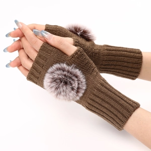 Détail de mitaines en maille marron foncé avec un pompon en fausse fourrure bicolore