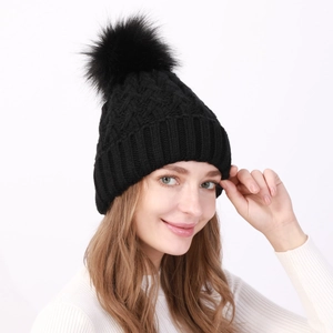 Dettaglio di un berretto nero in maglia da donna con morbido pompon in ecopelliccia