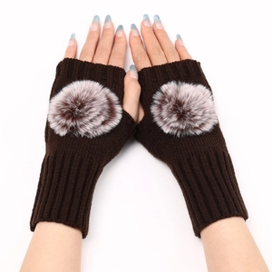 Détail de gants tricotés sans doigts marron café avec un grand pompon en fausse fourrure