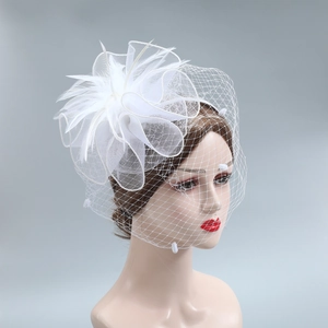 Detailed macro of a white bridal fascinator with layered mesh, feathers and a delicate veil