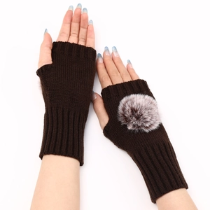 Détail de gants en tricot marron foncé avec pompons en fausse fourrure sur le dessus