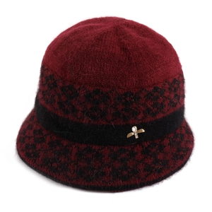 Detail view of burgundy knitted bucket hat with leopard pattern and gold bee brooch