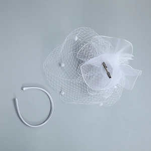 Close-up of white feather bridal fascinator clip and satin headband set for wedding
