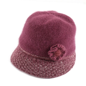 Detail of warm magenta knitted bucket hat with plush flower and thick fur texture