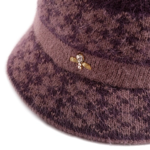 Close-up of purple knit hat with wool texture and golden bee ornament with rhinestones