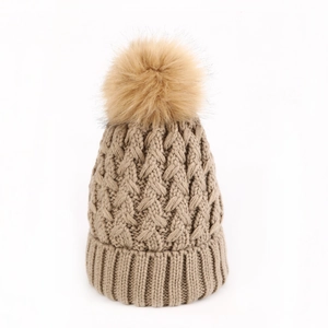 Dettaglio della maglia a trecce spesse e del pompon di pelliccia sintetica sul cappello