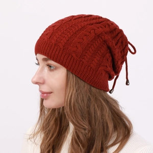 Detail of dark red cable knit beanie featuring adjustable drawstring and soft texture