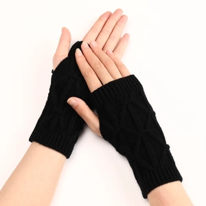 Détail de mitaines noires en tricot montrant le motif de losanges texturé en gros plan