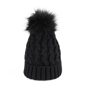 Dettaglio berretto nero in maglia a trecce con pompon in ecopelliccia e bordo