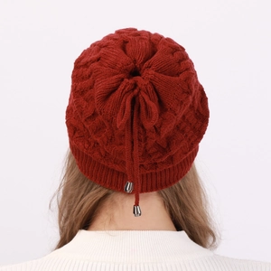 Detail of burgundy knit beanie featuring cable pattern and drawstring with metal toggles