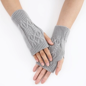 Gros plan sur des mitaines gris clair en tricot torsadé montrant la texture douce de la laine
