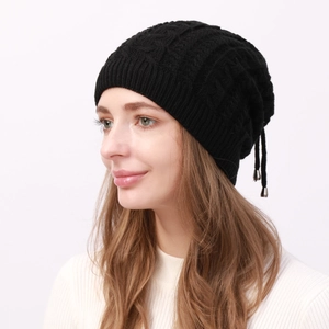 Detail of black cable knit beanie with thick texture and dual adjustable drawstrings