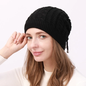 Detail of black cable knit beanie featuring decorative metal buckle and warm texture