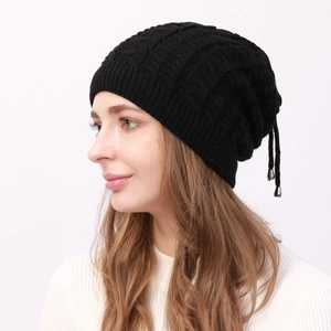 Detail of black cable-knit beanie with adjustable drawstring and metal pendants