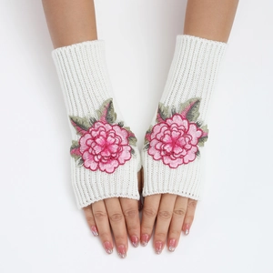 Détail de gants tricotés blancs sans doigts avec broderie florale de pivoine rose
