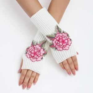 Gros plan de mitaines en tricot côtelé blanc avec broderie florale rose et feuilles