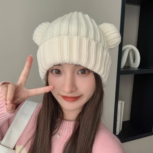 Close-up of beige knit beanie with cute bear ears and thick ribbed texture detail
