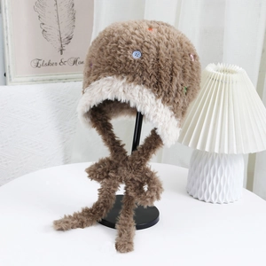 Dettaglio del cappello invernale in peluche marrone e crema con bottoni colorati