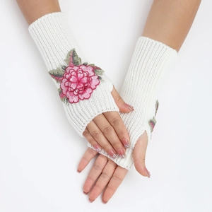 Détail de gants tricotés blancs sans doigts avec une broderie florale rose délicate