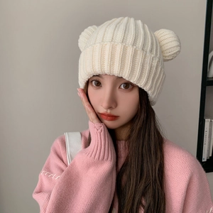 Detail shot of white chunky knit beanie featuring cute bear ears and a wide folded cuff