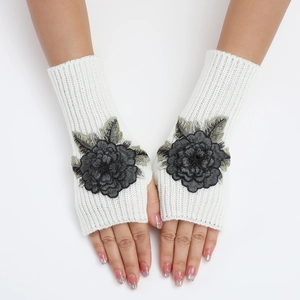 Gros plan de mitaines en tricot blanc avec broderie détaillée de fleurs noires