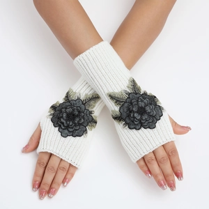 Détail de mitaines en maille blanche avec broderie florale noire et motif côtelé