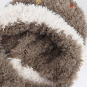 Dettaglio macro del cappello di peluche bicolore con bottoni colorati e texture soffice