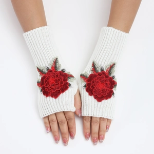 Détail macro de mitaines en maille blanche avec broderie florale rouge vif