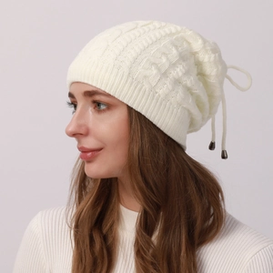 Detailed knit texture of white cable knit beanie featuring an adjustable drawstring tassel