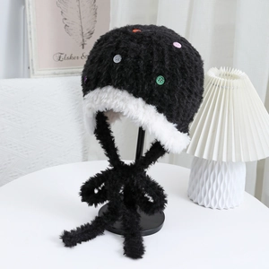 Dettaglio del cappello con paraorecchie in peluche bianco e nero con bottoni colorati